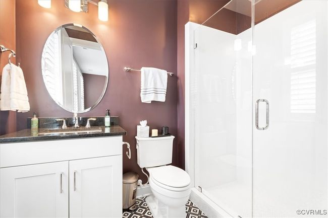 Bathroom with toilet, vanity, tile patterned floors, and a stall shower | Image 31