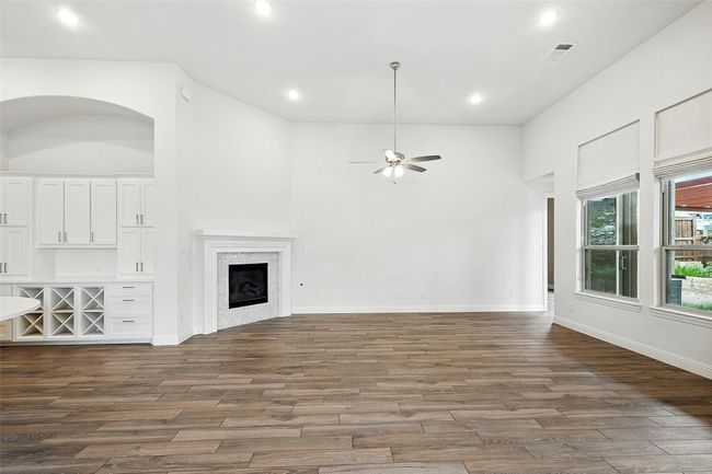 Unfurnished living room featuring tile floors, a tile fireplace, ceiling fan, recessed lighting, and a high ceiling | Image 12