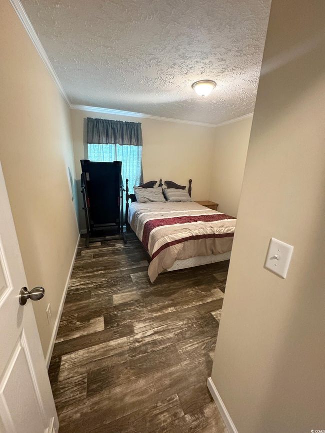 Bedroom with wood finished floors, a textured ceiling, and crown molding | Image 27