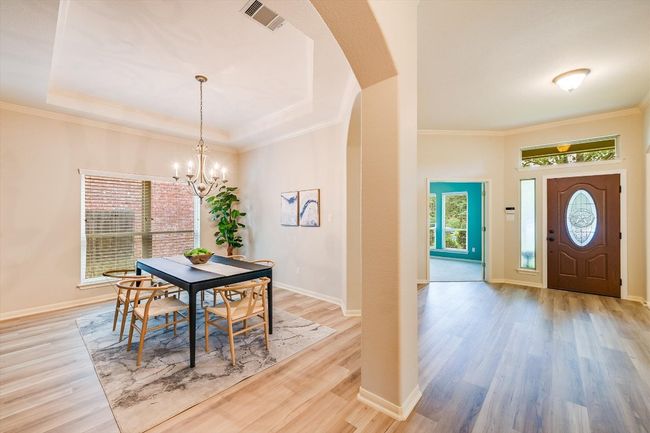 Dining space with light wood finished floors, plenty of natural light, arched walkways, a chandelier, and ornamental molding | Image 13