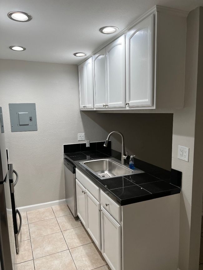 Washroom with baseboards, electric panel, recessed lighting, light tile patterned floors, and a sink | Image 7