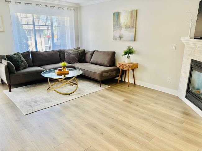 Living area featuring crown molding, a glass covered fireplace, and light wood finished floors | Image 5