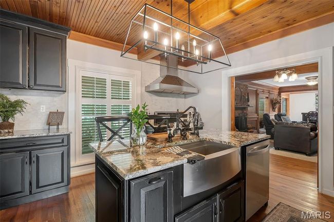Kitchen featuring stainless steel dishwasher, a chandelier, wall chimney exhaust hood, dark wood-type flooring, and wood ceiling | Image 47