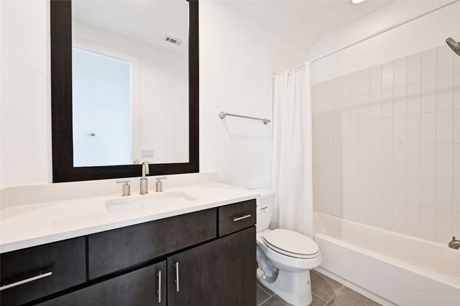 Second level guest bathroom with vanity, shower / bath combination with curtain, and tile patterned flooring | Image 21