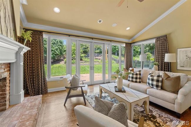 Living room featuring healthy amount of natural light, crown molding, a fireplace with raised hearth, lofted ceiling, and recessed lighting | Image 4