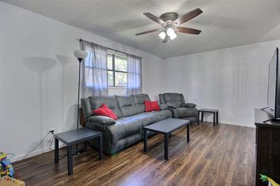 Living room with a textured ceiling, dark hardwood / wood-style floors, and ceiling fan | Image 3