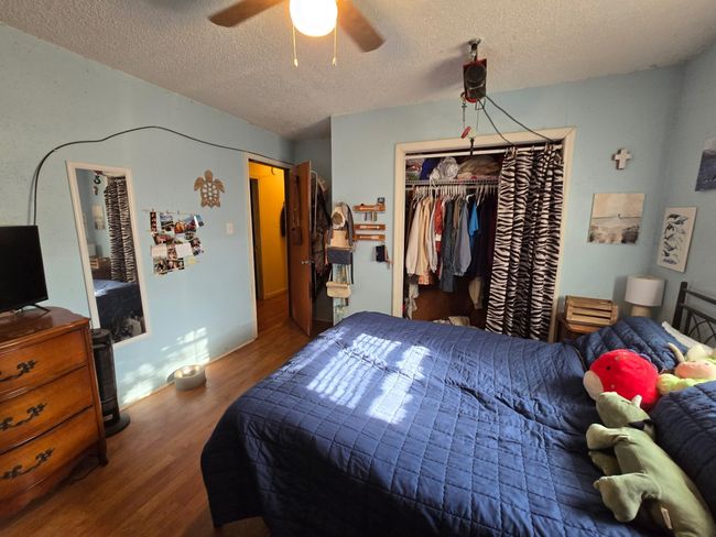 Bedroom with wood finished floors, a textured ceiling, ceiling fan, and a closet | Image 23