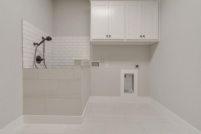 Clothes washing area featuring cabinets, washer hookup, electric dryer hookup, hookup for a gas dryer, and light tile patterned flooring | Image 30