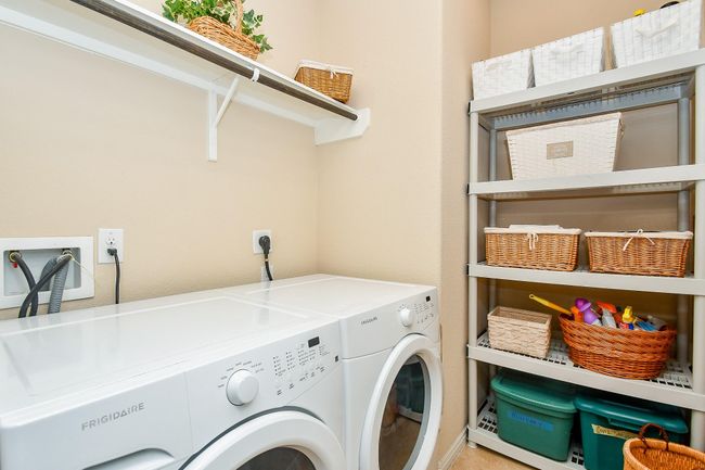 Laundry room featuring a washer, dryer, ample shelving with wicker baskets for storage, and a clean, neutral color scheme. | Image 26