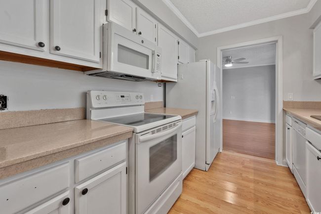 Unfurnished room featuring crown molding, ceiling fan, wood-type flooring, and a textured ceiling | Image 4