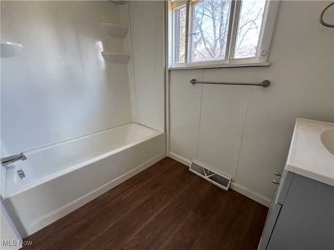 Bathroom featuring baseboards, visible vents, wood finished floors, vanity, and shower / washtub combination | Image 21