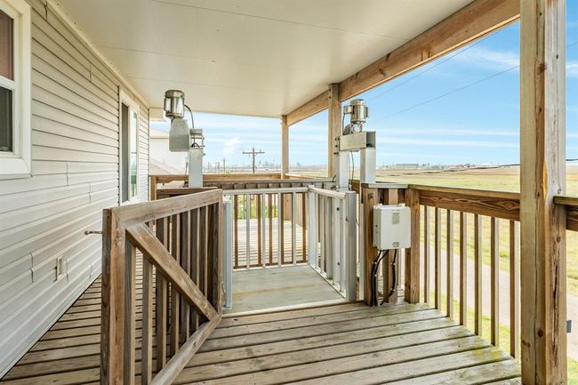 This photo showcases the back covered wooden deck with railing, providing expansive bay views. Ideal for relaxing and enjoying outdoor scenery while enjoy the convenience of a lift. | Image 21