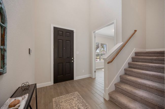 Foyer featuring wood finished floors, baseboards, stairway, and a high ceiling | Image 19