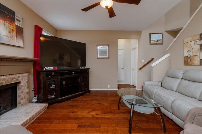 Living area featuring a brick fireplace, baseboards, wood finished floors, a ceiling fan, and lofted ceiling | Image 10