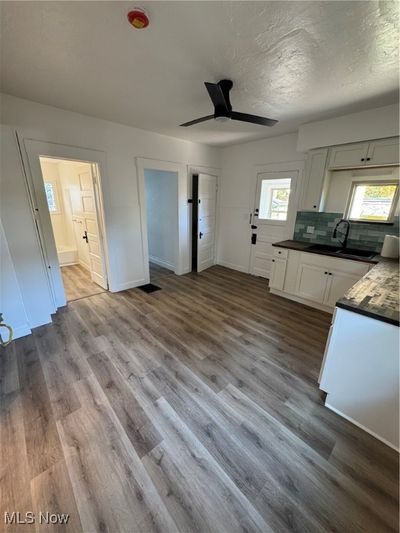 Kitchen featuring ceiling fan, sink, tasteful backsplash, light hardwood / wood-style flooring, and white cabinets | Image 3