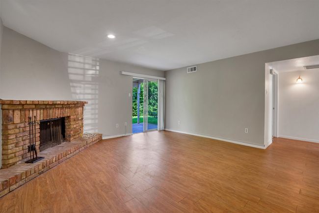 Unfurnished living room featuring finished floors, a brick fireplace, and recessed lighting | Image 4