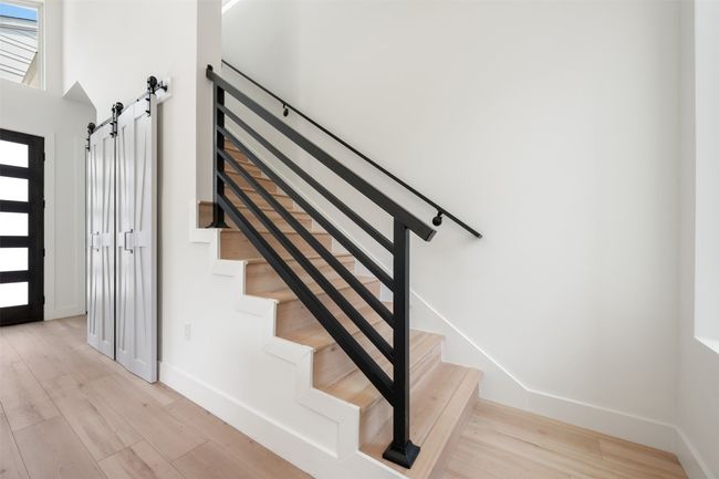 Stairway featuring a barn door, wood finished floors, baseboards, and a towering ceiling | Image 18