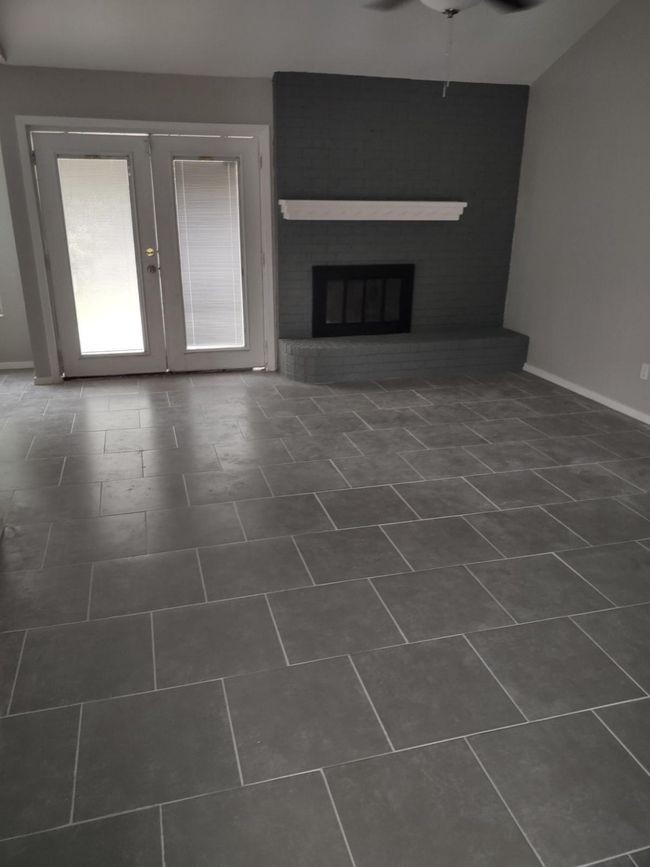 Unfurnished living room with french doors, ceiling fan, a brick fireplace, and dark tile patterned floors | Image 13