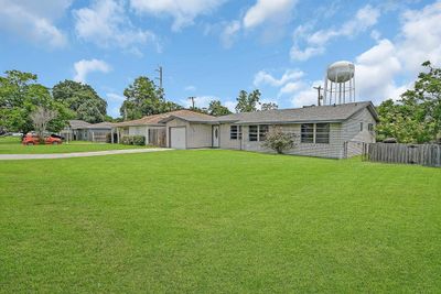 You're looking at a single-story brick home featuring a spacious, well-manicured lawn and an attached garage. The neighborhood appears peaceful, and there's a water tower in the background, indicating proximity to community facilities. | Image 1