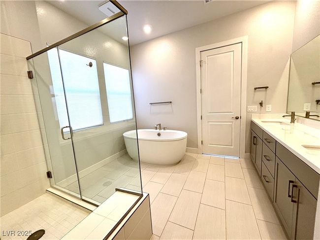 Full bathroom featuring tile patterned floors, a shower stall, double vanity, a freestanding tub, and a sink | Image 25