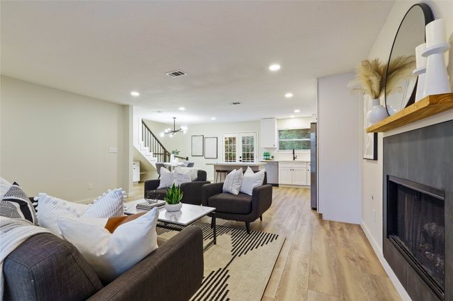 Living area featuring recessed lighting, a chandelier, a fireplace, light wood finished floors, and visible vents | Image 7