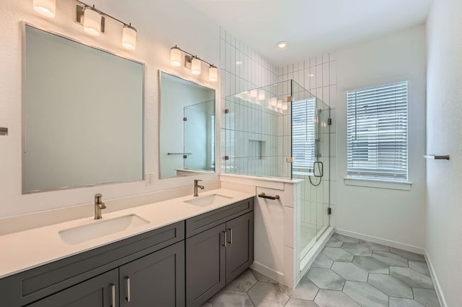 Full bathroom featuring double vanity, a sink, a stall shower, and tile patterned floors | Image 15