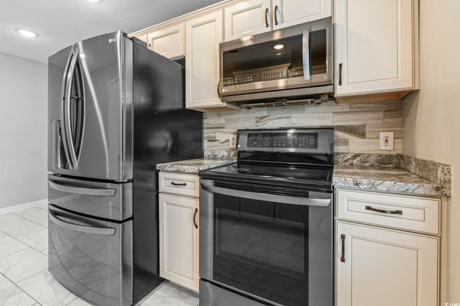 Kitchen with stainless steel appliances, light marble finish flooring, tasteful backsplash, light stone countertops, and recessed lighting | Image 9