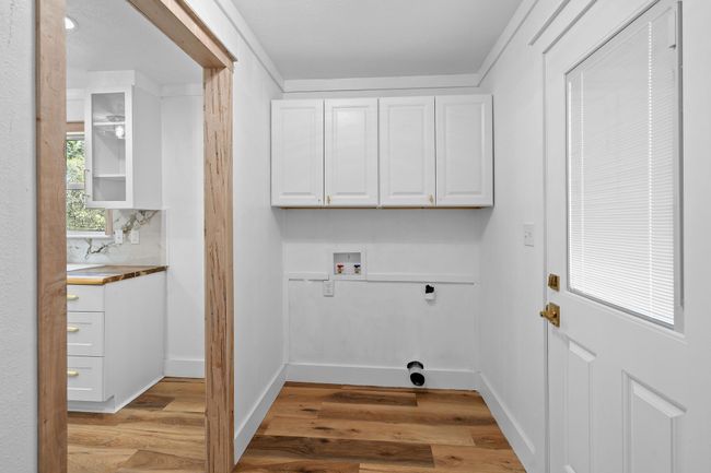 Clothes washing area featuring cabinet space, light wood-style flooring, electric dryer hookup, and hookup for a washing machine | Image 23