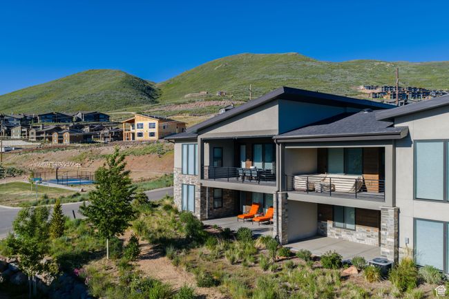 Back of property featuring stone siding, stucco siding, a balcony, and a patio | Image 4