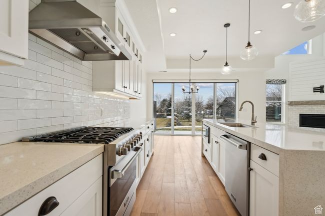 Kitchen with a sink, stainless steel appliances, decorative backsplash, and wall chimney range hood | Image 14