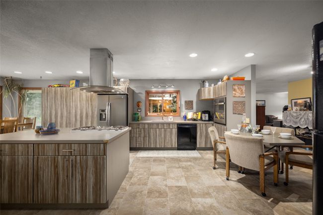 Kitchen featuring stainless steel appliances, island range hood, modern cabinets, light countertops, and a sink | Image 24