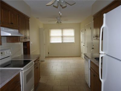 Kitchen with ceiling fan, backsplash, white appliances, and light tile patterned floors | Image 2