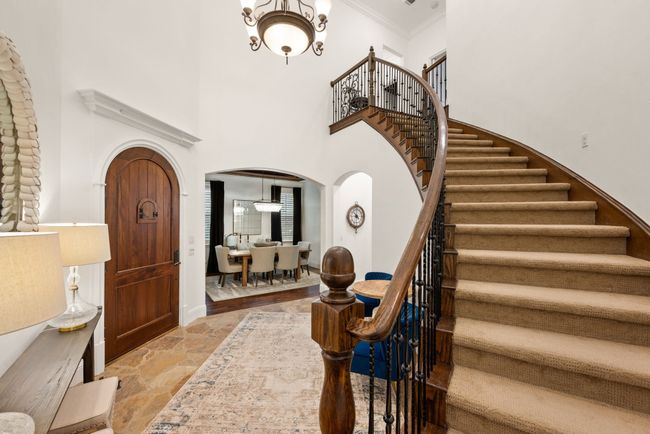 The iron baluster staircase with wood landing leads to secondary bedrooms and a media room | Image 23