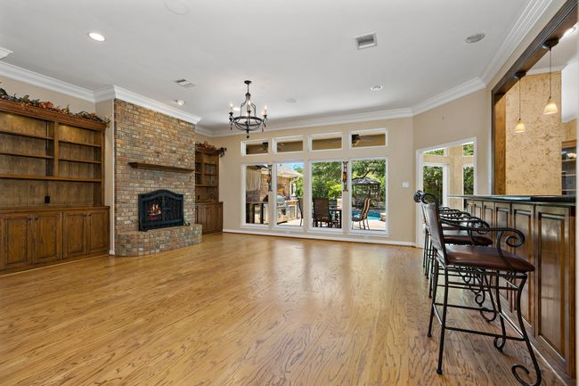 Living area with gas fireplace, crown molding, wood floors, and recessed lighting | Image 9