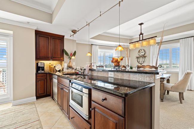 Kitchen featuring a peninsula, a tray ceiling, healthy amount of natural light, crown molding, and tasteful backsplash | Image 20