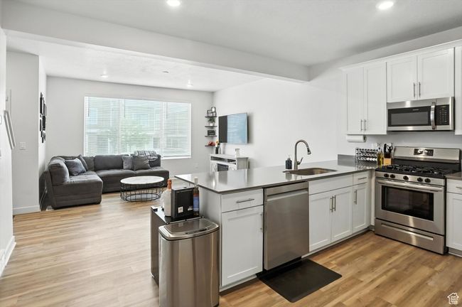 Kitchen with stainless steel appliances, a peninsula, open floor plan, recessed lighting, and new light wood-style LVP floors | Image 31