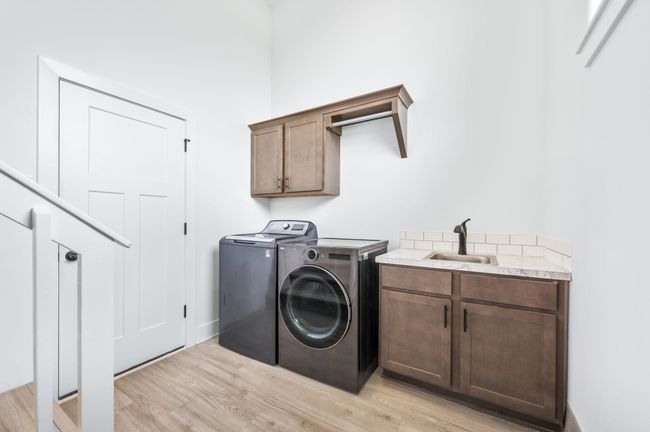 Washroom with independent washer and dryer, cabinet space, light wood-style flooring, and a towering ceiling | Image 22