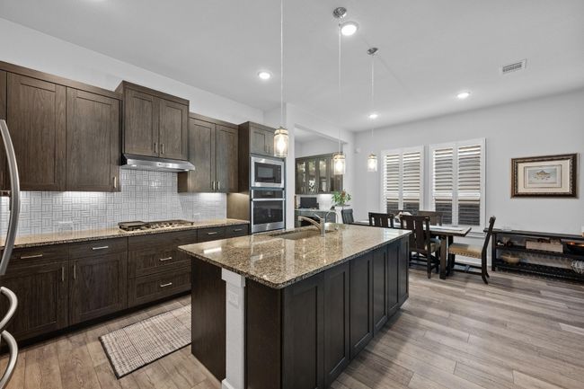 This kitchen is a chef's dream. Double ovens, five burner gas range, grey finish sink, and soft close cabinets. | Image 8