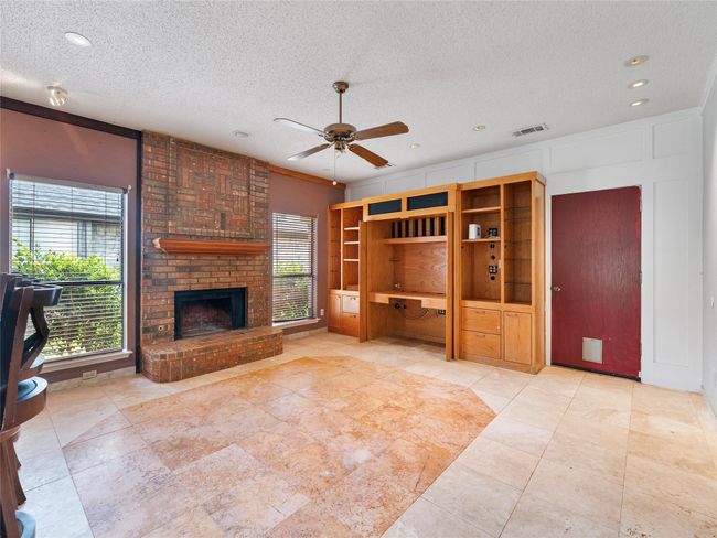 Unfurnished living room featuring a ceiling fan, a textured ceiling, a brick fireplace, recessed lighting, and a desk | Image 12