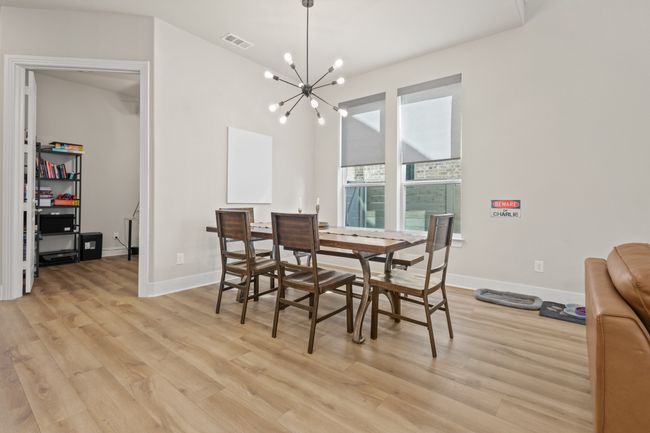 Dining area with light wood finished floors, visible vents, baseboards, and an inviting chandelier | Image 11