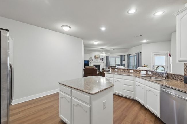 Kitchen featuring stainless steel appliances, a fireplace, a ceiling fan, light wood-type flooring, and recessed lighting | Image 13