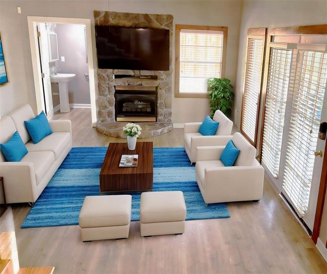 Cozy living room featuring a stone-accented fireplace and an included large screen TV. (virtually staged) | Image 18
