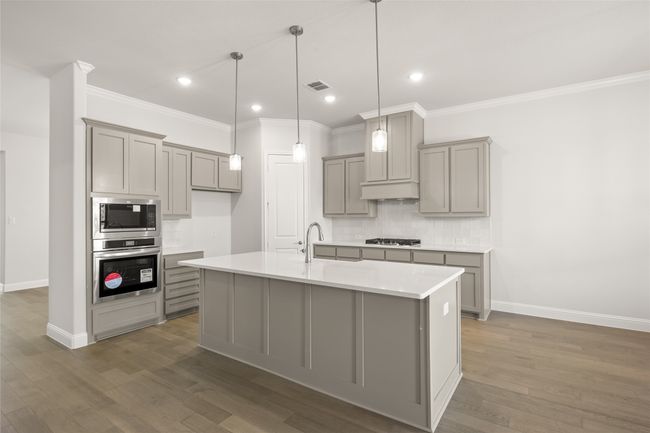 Kitchen with stainless steel appliances, gray cabinets, crown molding, decorative backsplash, and baseboards | Image 6