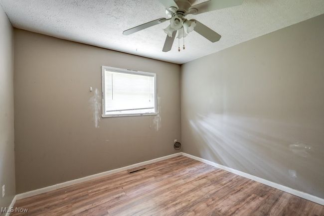 Spare room featuring wood finished floors, a ceiling fan, baseboards, and a textured ceiling | Image 32