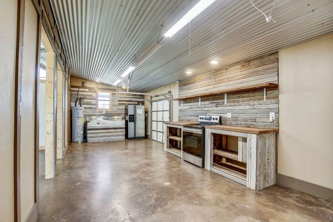 Kitchen with water heater, wooden walls, butcher block countertops, finished concrete floors, and stainless steel appliances | Image 24