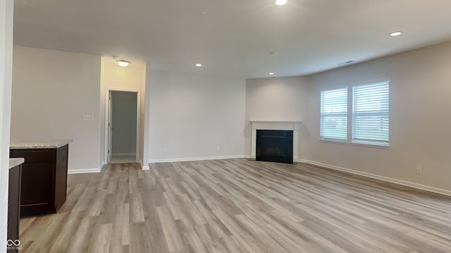 unfurnished living room with recessed lighting, a fireplace with flush hearth, light wood-style flooring, and baseboards | Image 5