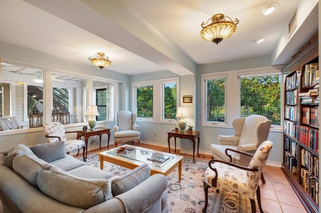 An Inviting First-Floor Living Haven: The tasteful use of tile and brick flooring throughout the public spaces on this level not only enhances the visual appeal but also promotes a warm and inviting ambiance. One of two living spaces in the first level home. | Image 28