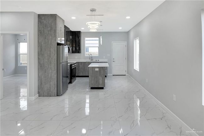 Kitchen with light countertops, marble finish floor, modern cabinets, appliances with stainless steel finishes, and a center island | Image 4