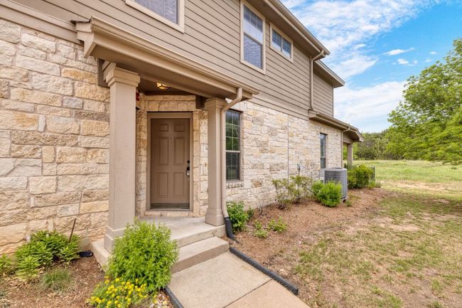 View of exterior entry with stone siding and cooling unit | Image 7