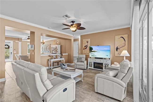 Living area featuring a ceiling fan, crown molding, light tile patterned floors, and baseboards | Image 16